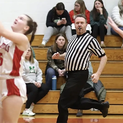 Kyle Fennell runs down the sideline while officiating a girls basketball game.