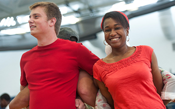 Two students in red shirts work on a team building exercise during Orientation.