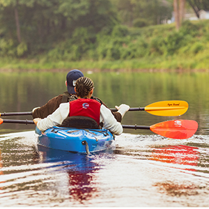 Two students row down the Grasse River in a blue kayak.