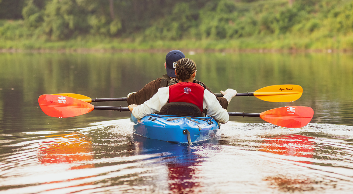Two students row down the Grasse River in a blue kayak.
