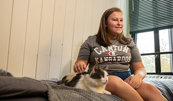 Taylor sits on her bed with pet cat, Hemlock (Hemmy).