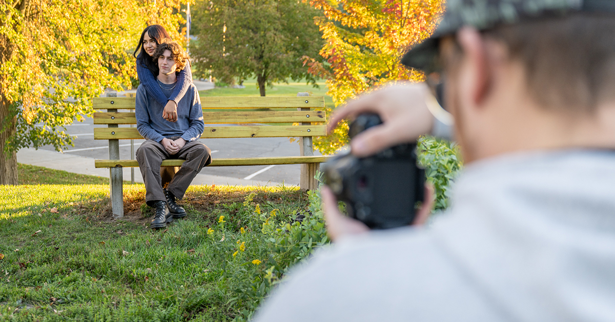 Jae Byun snaps a photo of a couple on bench during a photography portrait class.