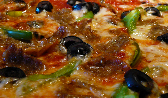 Pizza with black olives, green peppers, pepperoni, and sausage