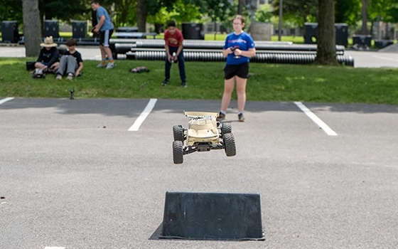 A student drives an RC Car off a ramp in the Nevaldine parking lot.