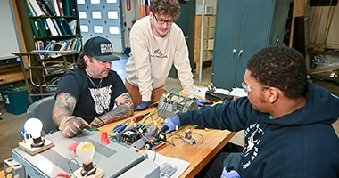 Three students work in the electrical construction management lab.