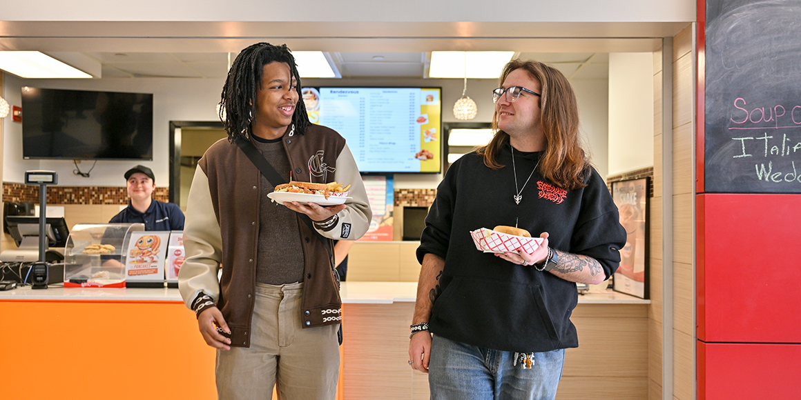 Two students are all smiles as they receive their food at Rendezvous dining center.