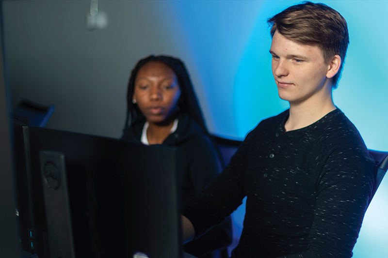 Two students work together on a desktop in the new Cybersecurity Lab.