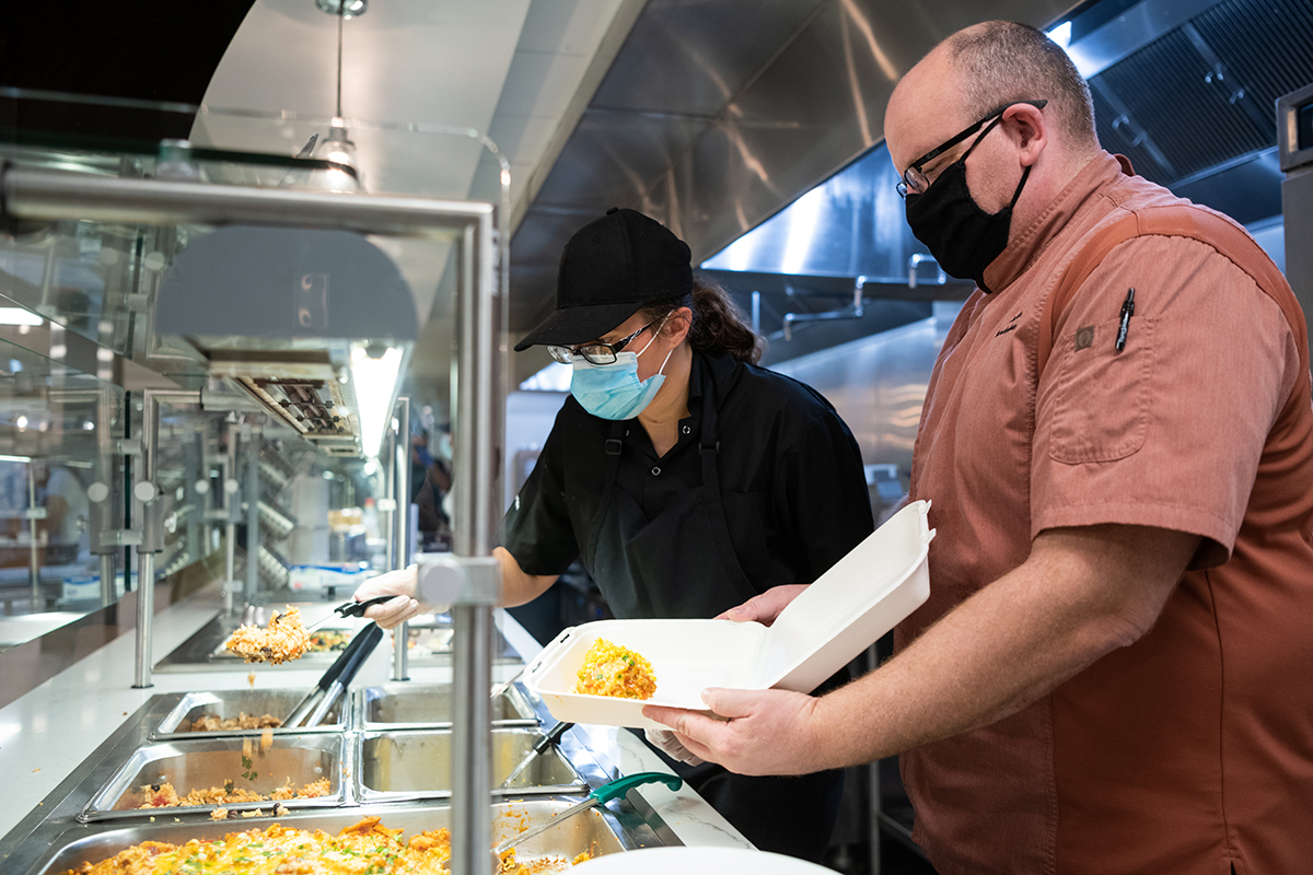 Two Chaney employees place food in a to-go container.