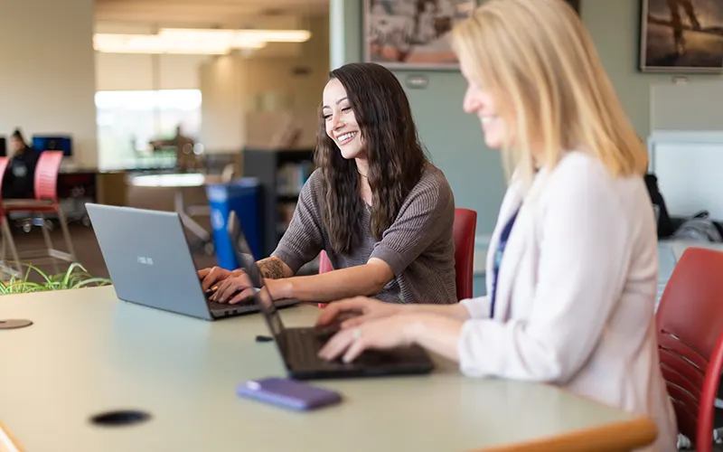 Two students study on their laptops in Southworth Library.