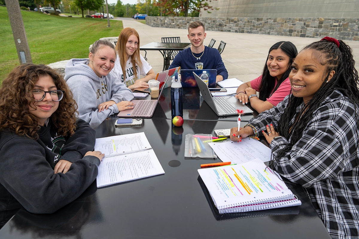 Smiling students study together outside Dana Hall.