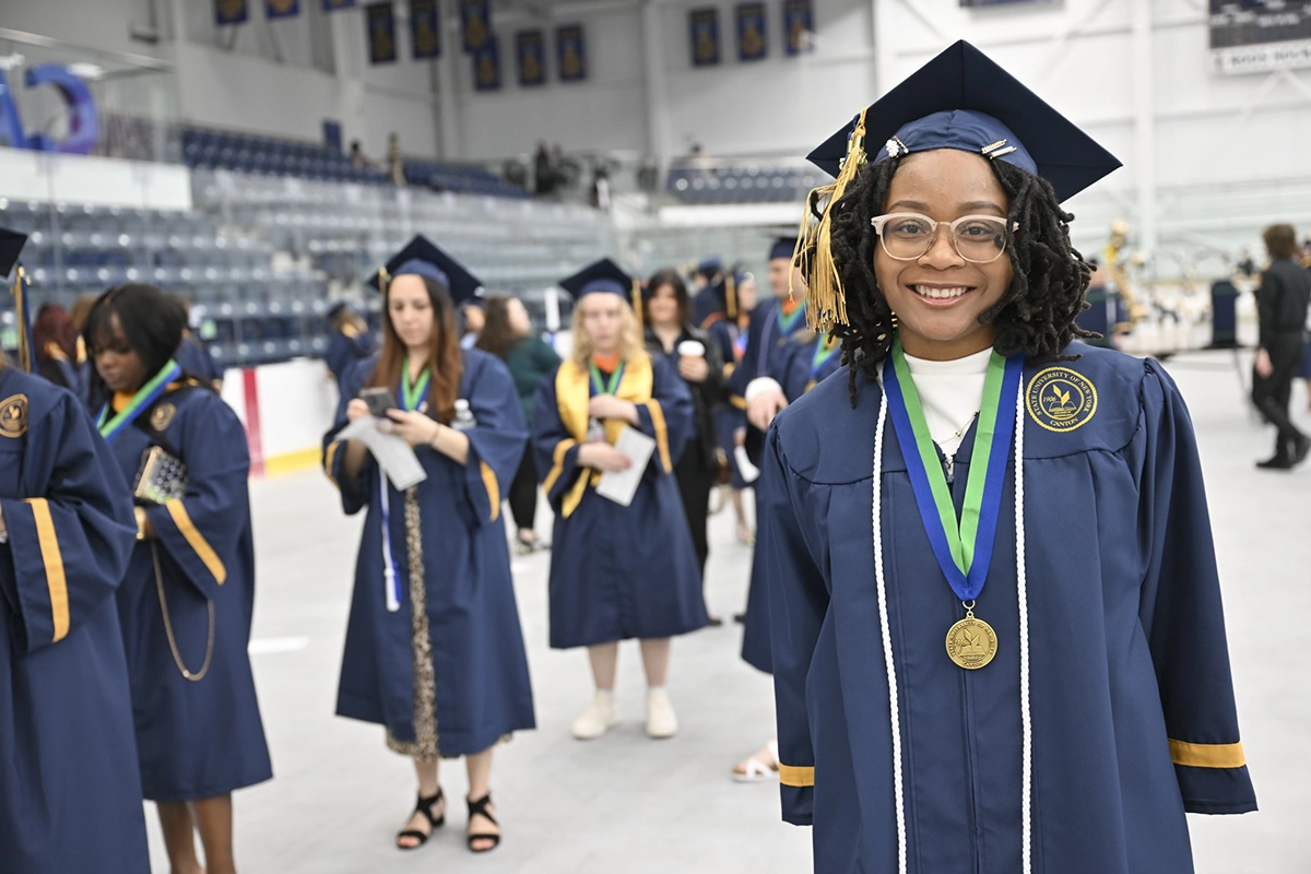 A graduate is all smiles while waiting for the Commencement 2025 ceremony to begin.