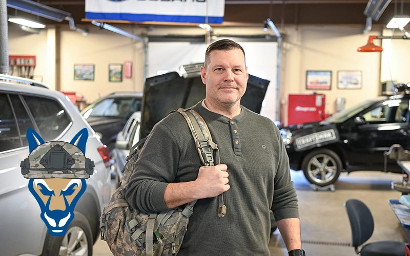 Eric Armstrong stands with a military backpack in the Automotive Lab.