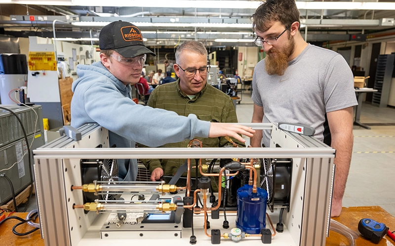 Jay Simmons instructs two students on the components of a heat pump.