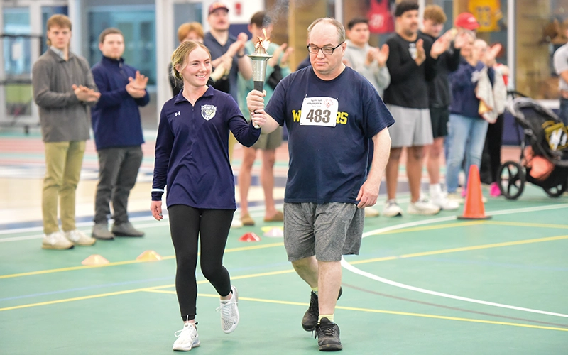 Women's Soccer forward Sydney Hoefer walks with the Special Olympics torchbearer.