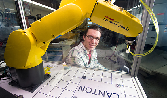 A student operates a yellow robotic arm.