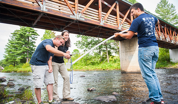 Adrienne Rygel helps two students take samples from the Grasse River.