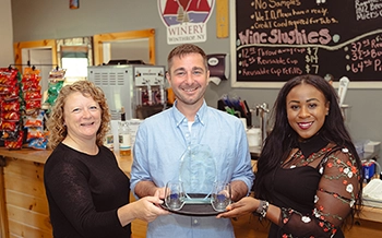 Michelle Collins, Matthew Whalen, and Sonya Smith pose with the SBDC 2023 Rural Business of the Year Award at High Peaks Winery.