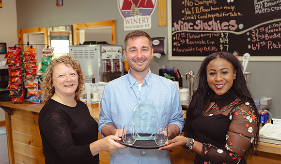 Michelle Collins, Matthew Whalen, and Sonya Smith pose with the SBDC 2023 Rural Business of the Year Award at High Peaks Winery.