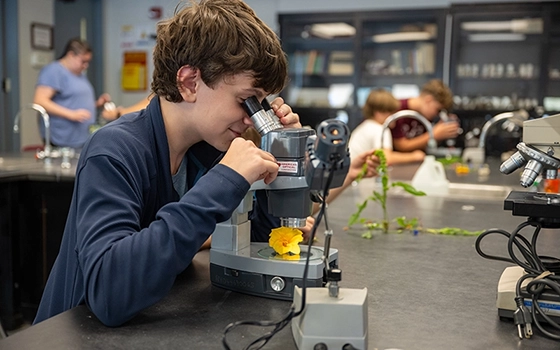 A camper looks through a microscope during science camp.