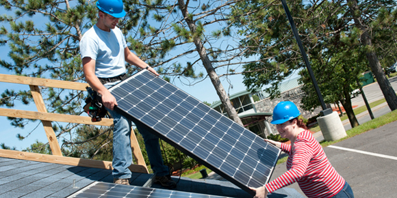 Students install solar panels on a demo roof.