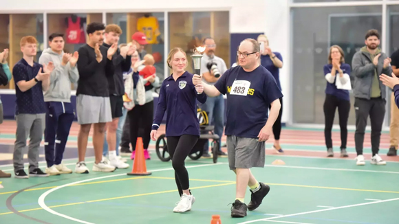 Sydney Hoefer, a member of the SUNY Canton women's soccer team and part of the leadership team for the SAAC, carries the torch with a Special Olympian.
