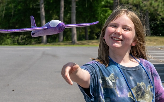 A camper flies a purple foam gilder outside.