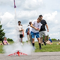 A camper launches a small rocket outside during STEM camp.