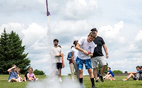 A camper launches a small rocket outside during STEM camp.