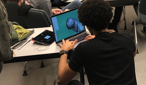 A students mocks-up a 3D design on a laptop.