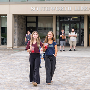 Two students enjoy iced Starbucks drinks as they depart Southworth Library.