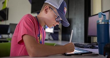 A camper sketches on an iPad in the Game Design and Development lab.