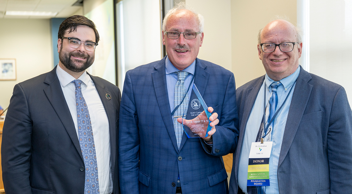 Carl Trainor accepts his Hall of Fame award from Vice President Geoffrey VanderWoude and President Zvi Szafran.