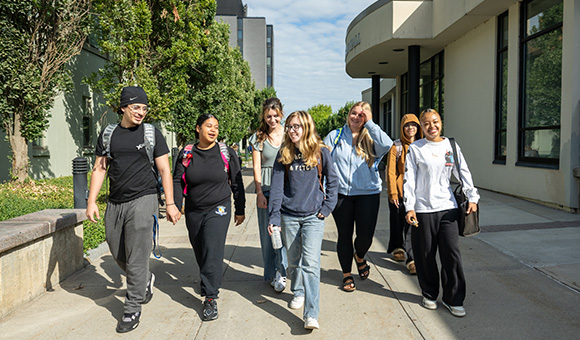 A group of seven TRiO students walk through the plaza outside Cook Hall.