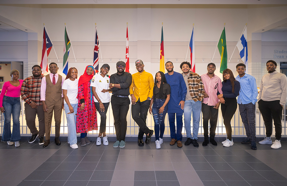 Cameroon Students stand in front of flags outside the International Programs office.