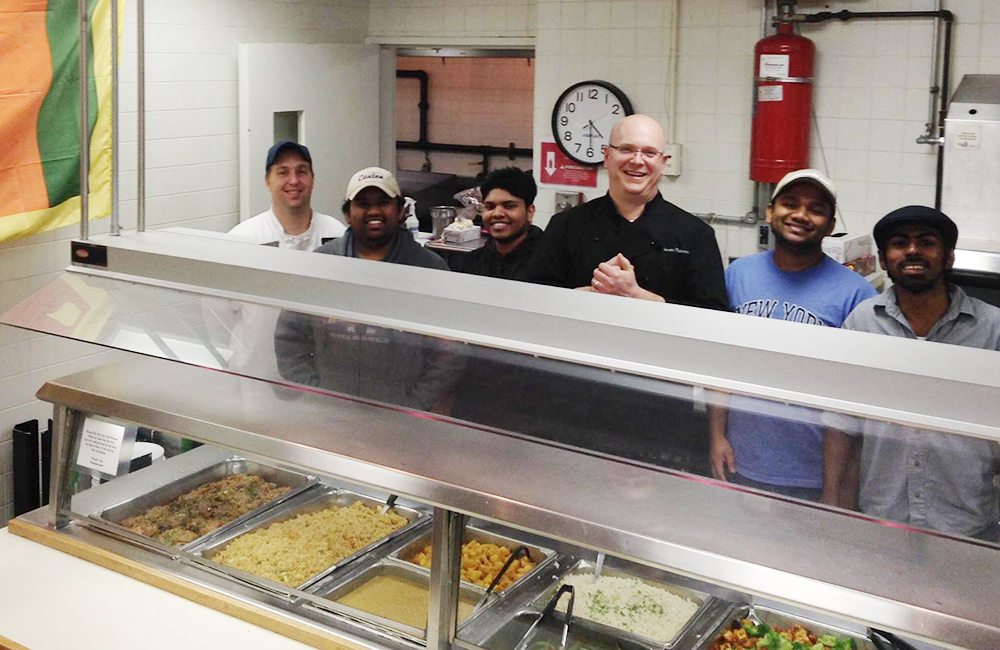 Sri Lankan students stand in kitchen with Steve Maiocco