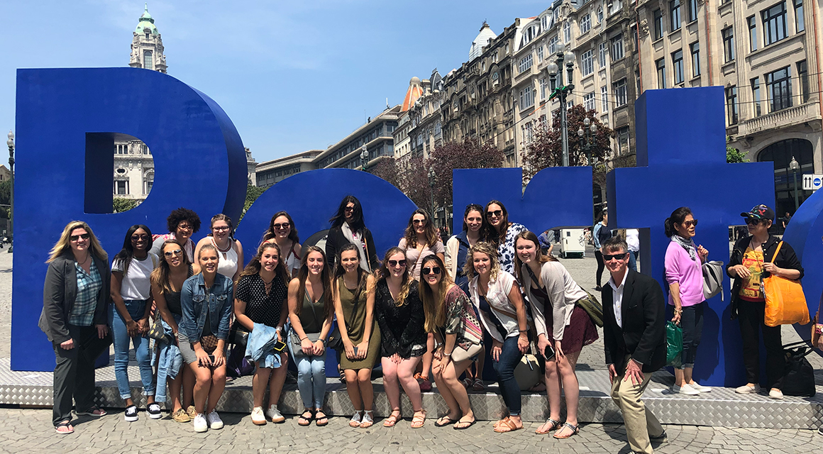 Students stand in front of a blue Porto sign in Portugal.